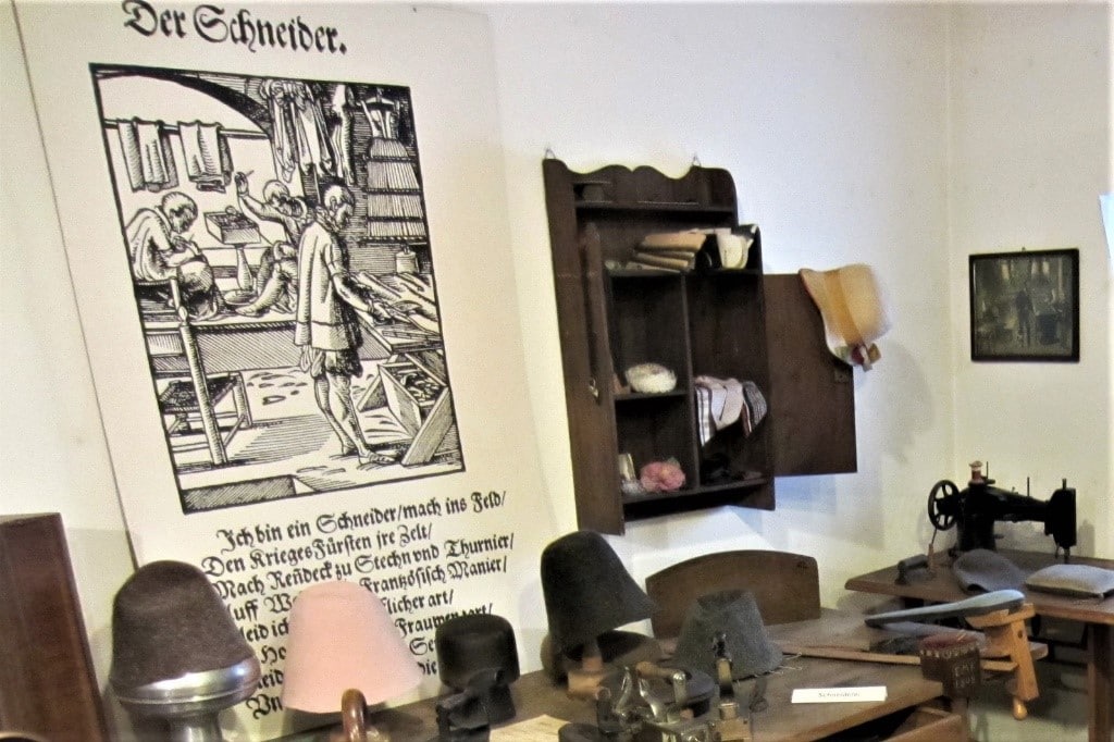 German Naming Customs by popular US online genealogists, Price Genealogy: image of a room decorated with old german hats, a german sign, a desk, and an antique black sewing machine. 